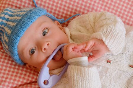 Cute baby in knitted hat and sweater playing with a rattleの写真素材