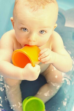 Cute baby bathing in tube and playing with plastic capsの写真素材