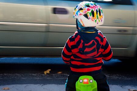 Little boy riding his pushbike in traffic without a parent supervision.の写真素材