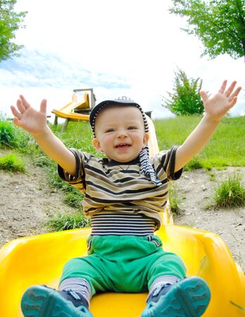 Happy toddler sliding down a long slide in the nature. Child concept.の写真素材