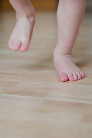 Baby foot running on a tiled floorの写真素材