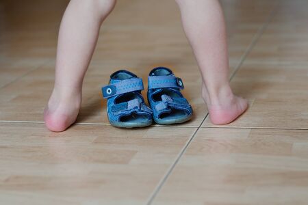 Contrast of barefoot kids legs and shoesの写真素材