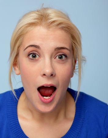 Portrait of beautiful surprised blonde girl on blueの写真素材