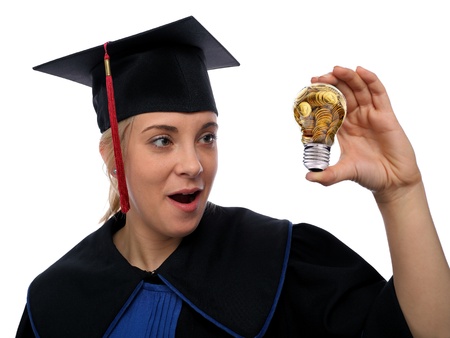 Beautiful girl in the graduation cap and glass bulb with golden coins in handの写真素材