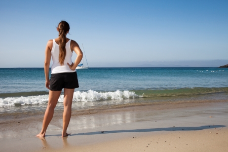 Young woman looks longingly at the waves in the seaの写真素材