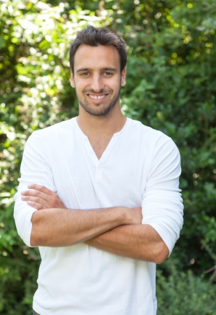 Laughing latin man with crossed arms in a park の写真素材