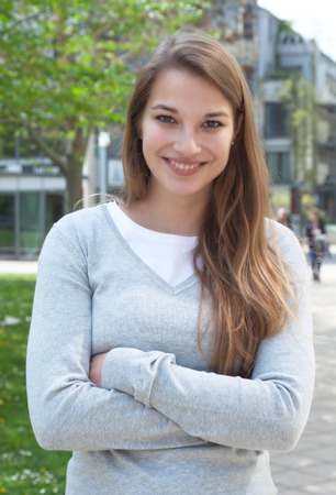 Standing young woman with crossed arms in casual clothes outsideの写真素材