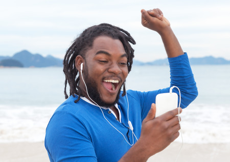 African american guy with dreadlocks listening to music at beachの写真素材