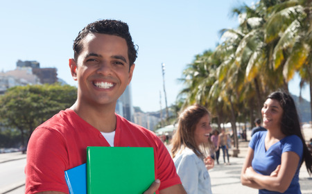 Latin male student with friends in the cityの写真素材