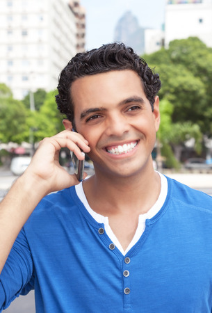 Laughing latin guy with cell phone in the cityの写真素材