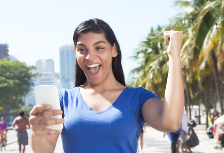 Attractive latin woman receiving good news on cellphoneの写真素材