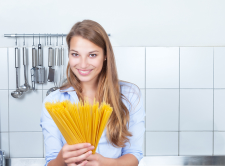 Laughing blonde woman with spaghetti at kitchenの写真素材