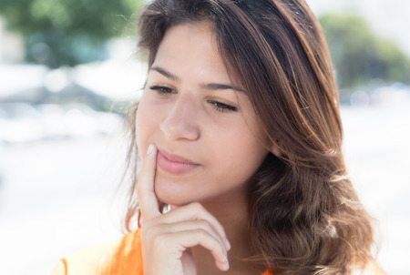 Thinking caucasian woman in a orange shirt