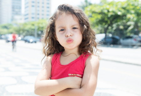 Courageous child in a red shirt outside looking at cameraの写真素材