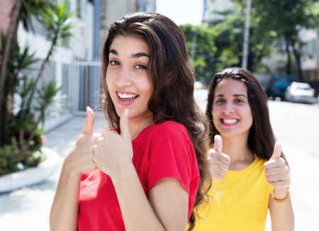 Two beautiful caucasian girls showing thumbs upの写真素材