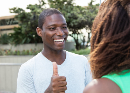 Laughing african guy showing thumb to his girlfriend
