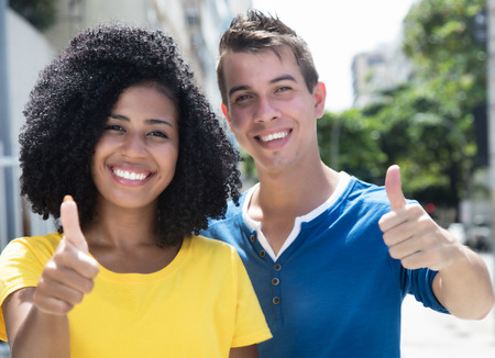 Laughing latin woman with curly black hair and boyfriend showing thumbの写真素材