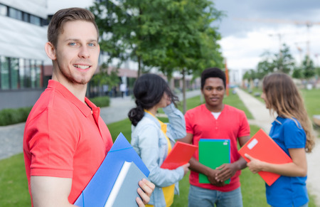 Laughing caucasian male student with stubble and multiethnic friends