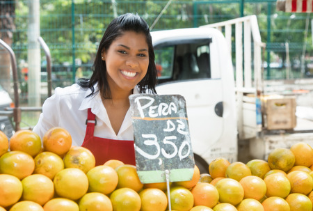 Happy mexican saleswoman with oranges on a farmers marketの写真素材
