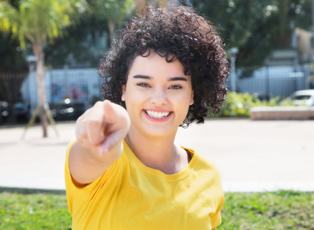 Caucasian girl with curly black hair pointing at cameraの写真素材