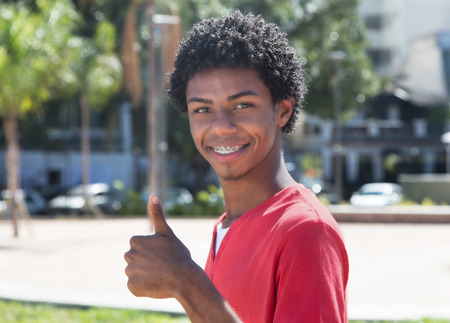 Latin american guy with dental braces showing thumbの写真素材