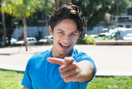 Caucasian guy in a blue shirt pointing at cameraの写真素材