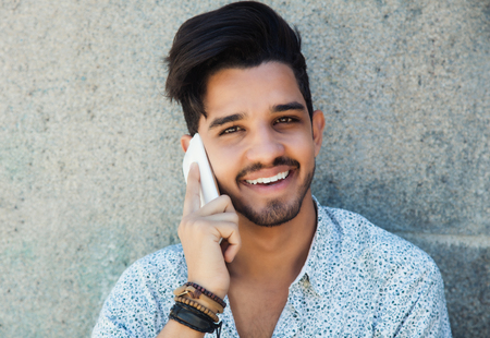 Handsome hipster with beard laughing at phoneの写真素材