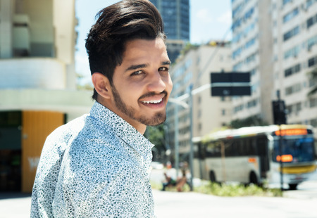 Handsome hipster with beard looking back in the cityの写真素材
