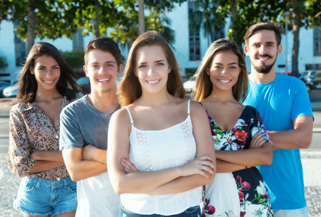 Blonde caucasian girl with international man and woman outdoor in the summer in the cityの写真素材