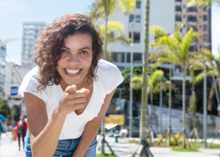 Beautiful hispanic woman pointing at camera outdoor in the summer in the cityの写真素材