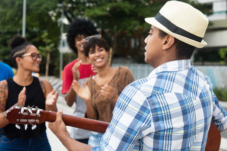 Joyful listening young people at a concert of street muscian outdoor in the city in the summerの写真素材