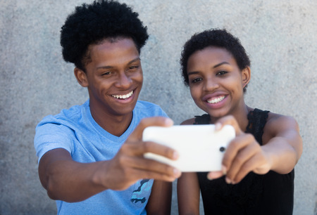 Joyful laughing african american couple taking selfie with phone outdoor in the summerの写真素材
