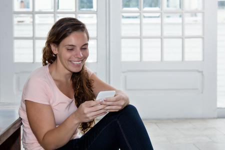 Laughing blond woman sending message with phoneの写真素材