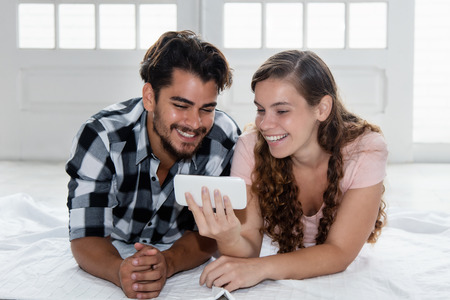 Latin man watching tv on phone  with caucasian girlfriendの写真素材