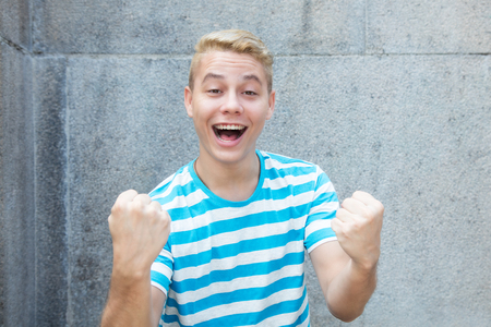 Cheering german young adult man with colored blond hairの写真素材