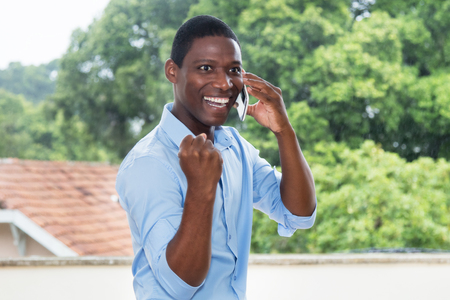 Cheering african businessman with mobile phoneの写真素材