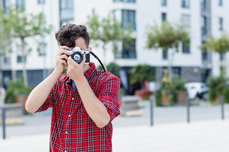 Hipster guy taking picture with retro cameraの写真素材