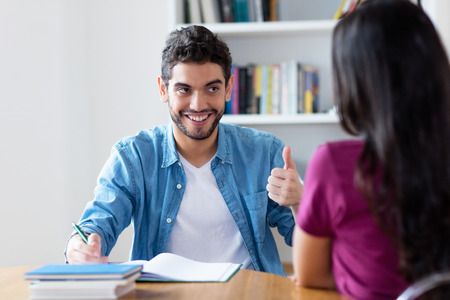 Laughing spanish male student preparing for exam on private lesson