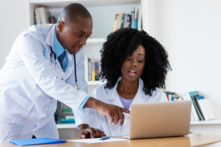African american male doctor and nurse talking about patient at hospitalの写真素材