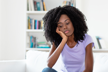 Sad and frustrated african american woman indoors at homeの写真素材