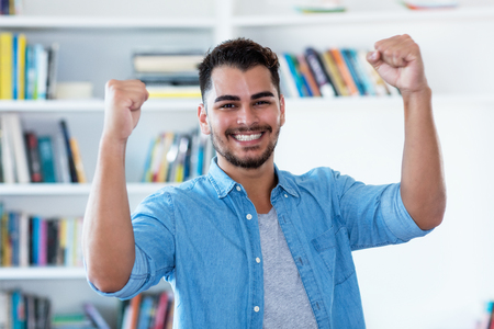 Cheering mexican hipster man with beard indoor at homeの写真素材