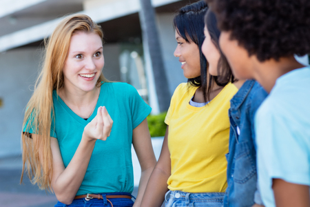 Beautiful young adult woman with red hair talking with girlfriendsの写真素材