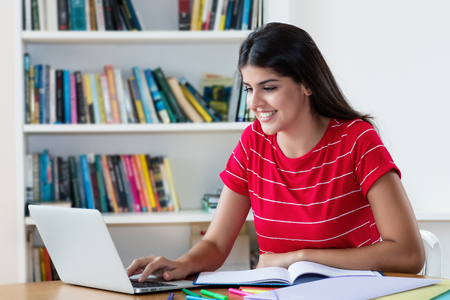 Laughing mexican female student learning on computerの写真素材
