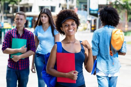 Happy african american young adult woman with students in cityの写真素材