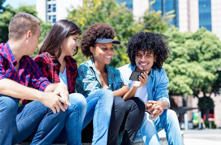 Happy hispanic and african american hipster young adult people with phone