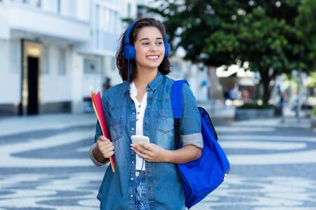 Pretty spanish female student with backpack and earphonesの写真素材