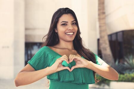 Latin american young adult woman showing heart with fingersの写真素材
