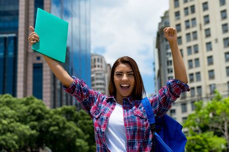 Cheering hispanic female student in city
