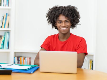 Laughing african american male student in quarantine at computerの写真素材