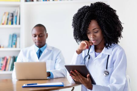African american medical student at digital tablet computer with male scientistの写真素材